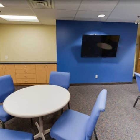 A training room with blue chairs and a painting on the wall for First Aid CPR.